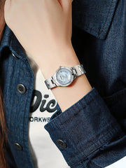 Silver watch on a wrist with a denim jacket and white shirt in the background