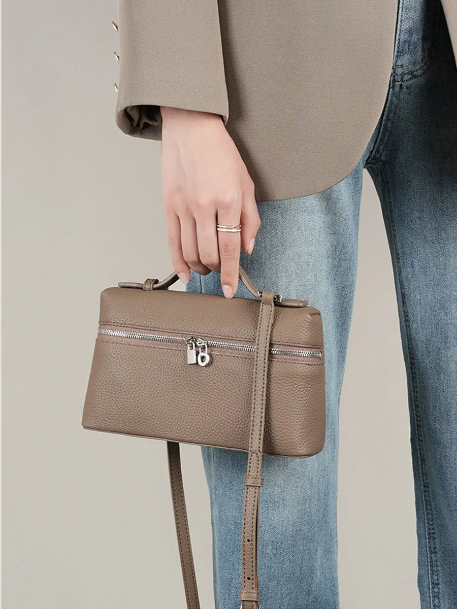 Person holding a brown handbag with a neutral background