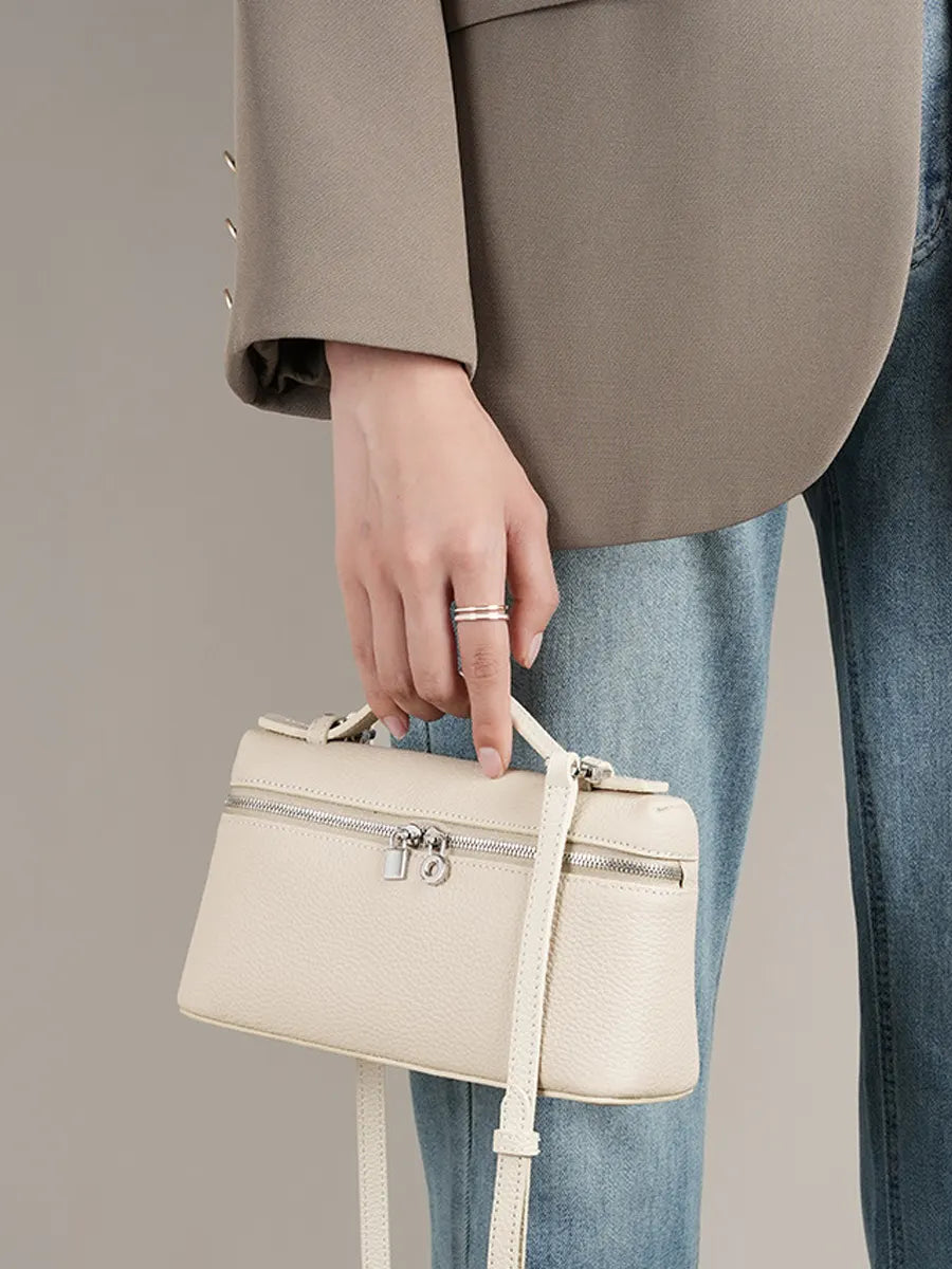 Person holding a beige handbag with a neutral background