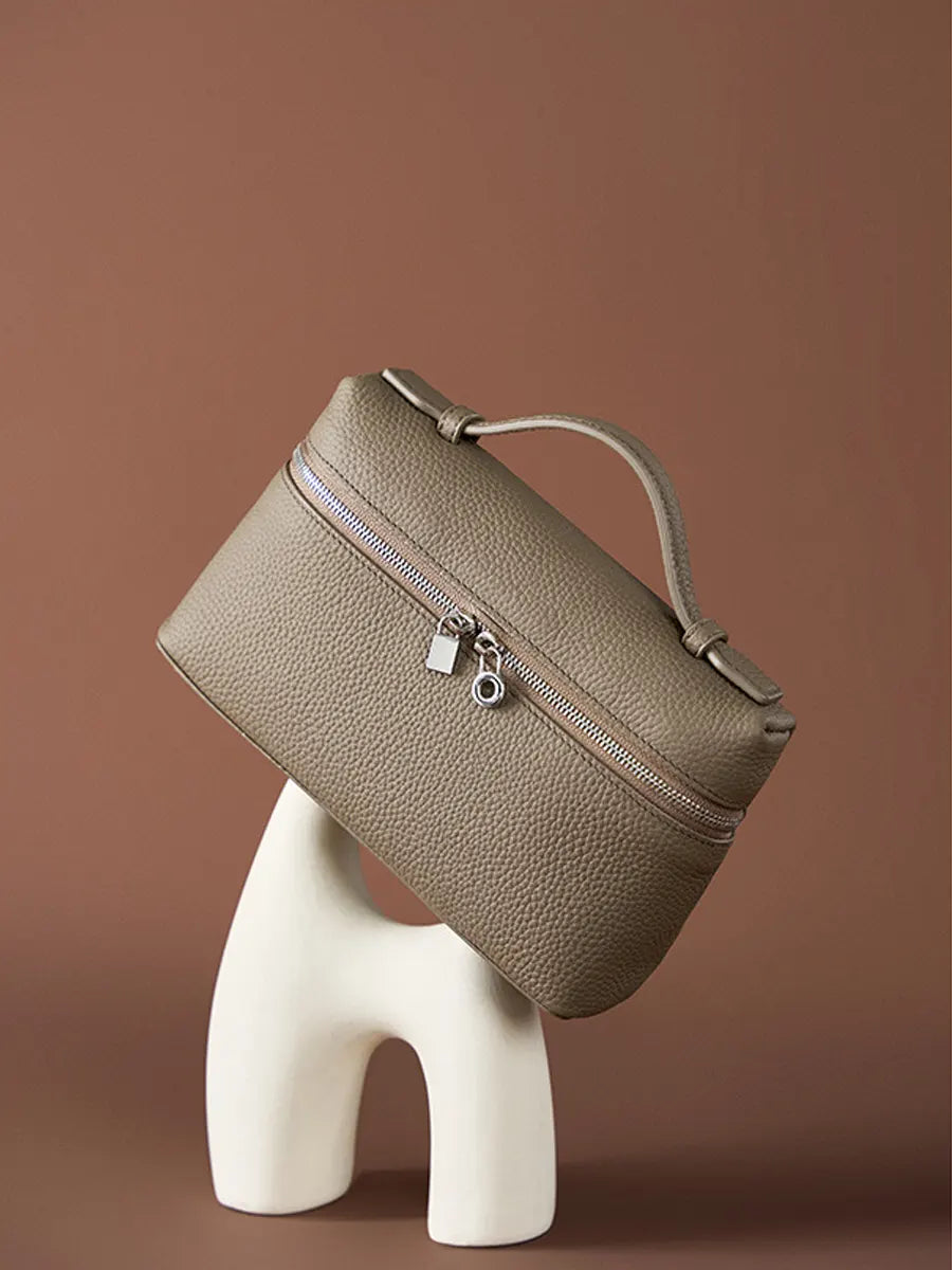 Brown textured handbag on a white stand against a brown background