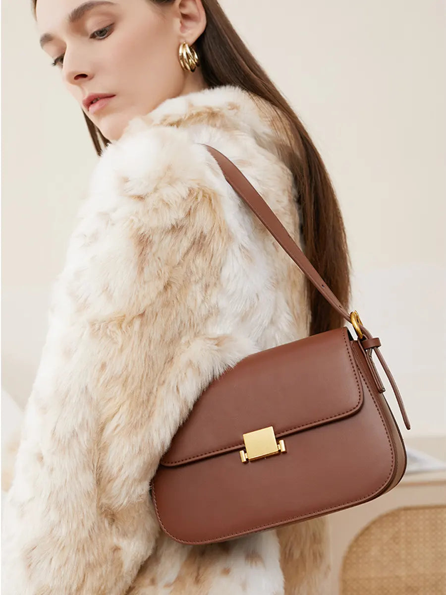 Woman wearing a fur coat with a brown handbag on a neutral background