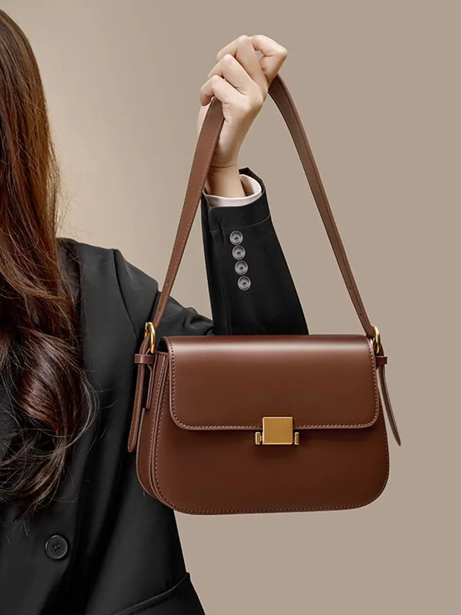 Brown handbag held by a person against a beige background