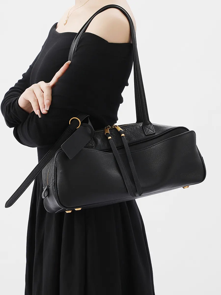 Person holding a black handbag against a white background