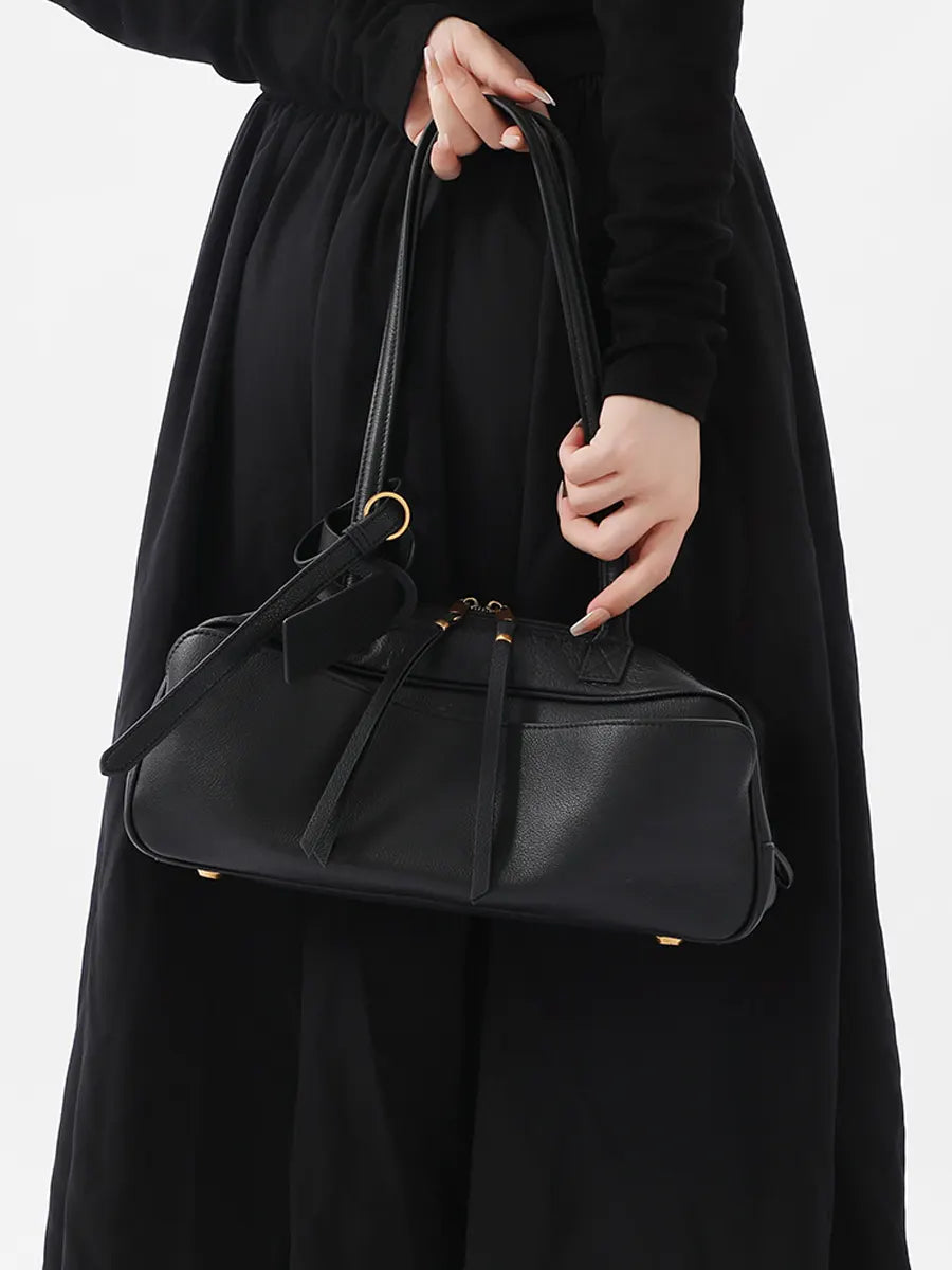 Person holding a black handbag against a plain background