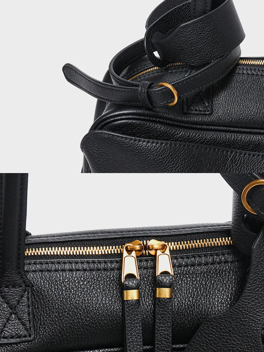 Close-up of a black leather bag with gold zipper pulls on a white background