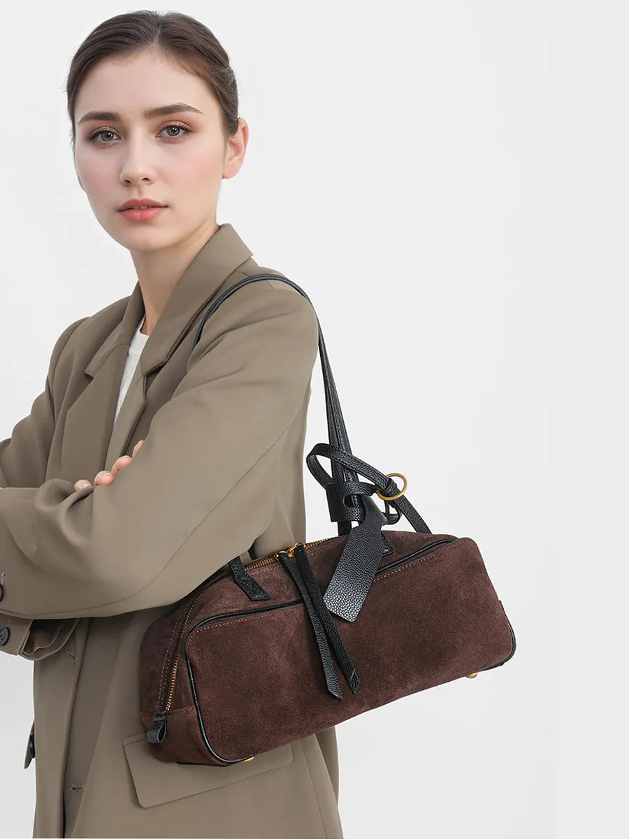 Woman holding a brown leather bag against a plain background