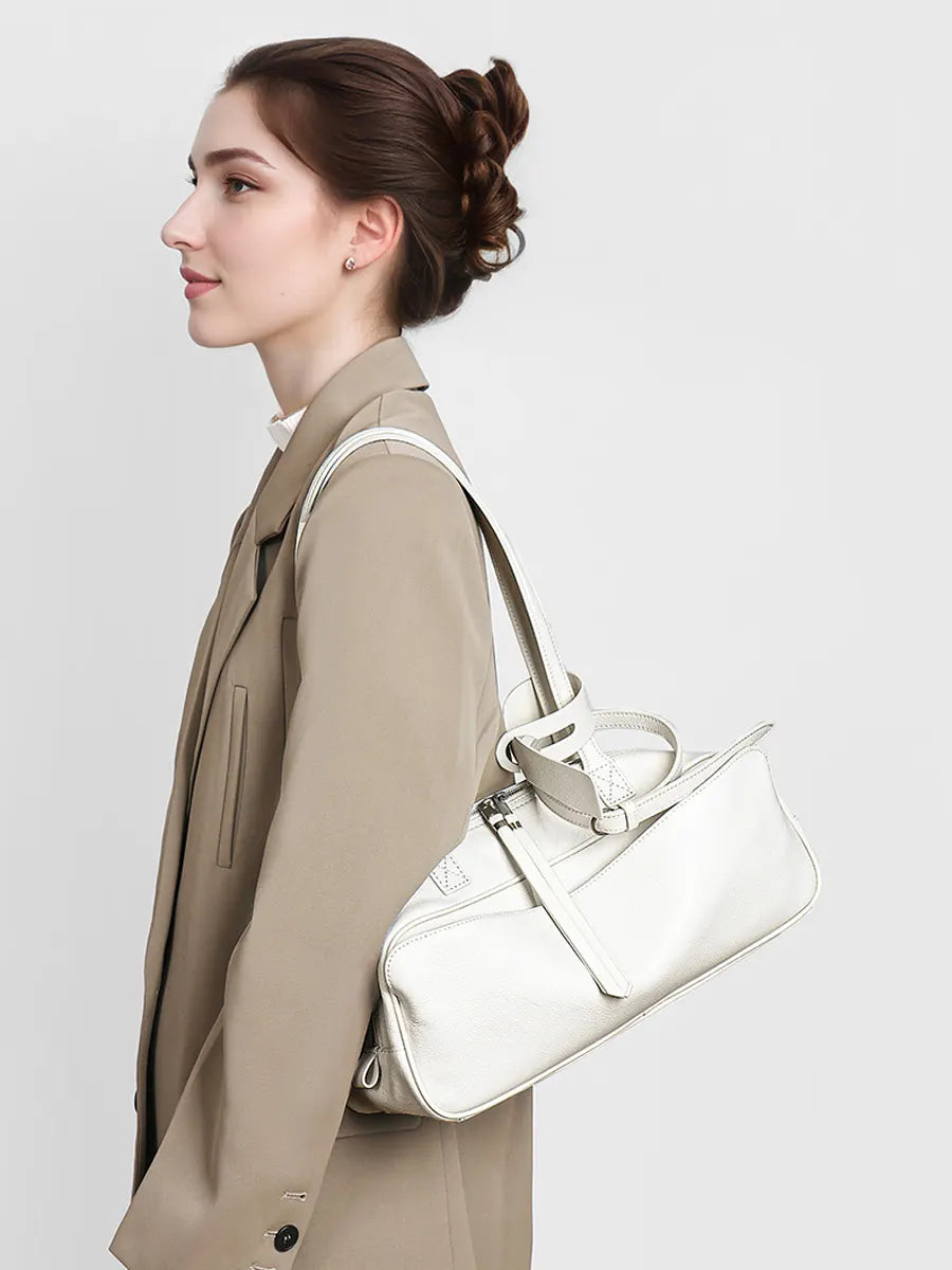 Woman carrying a silver handbag against a plain background