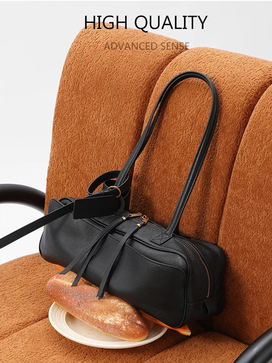Black handbag on a brown couch with bread on a plate
