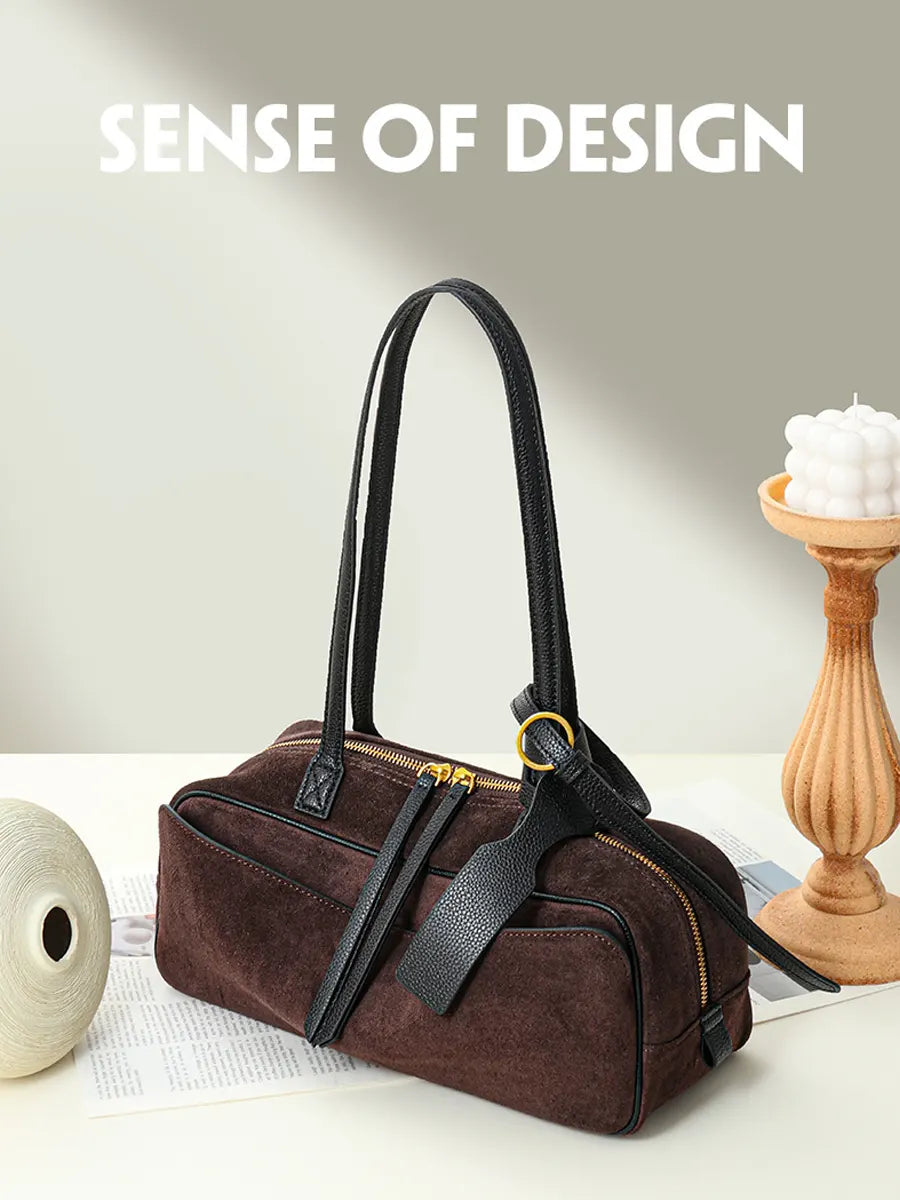Brown handbag with black straps on a light surface, with 'Sense of Design' text above.
