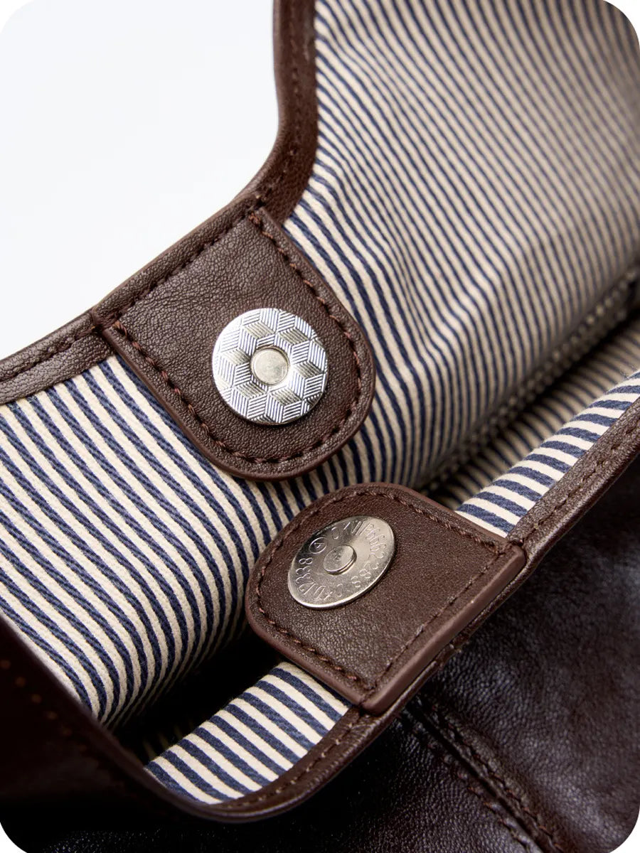 Close-up of a bag with striped fabric and brown leather straps.