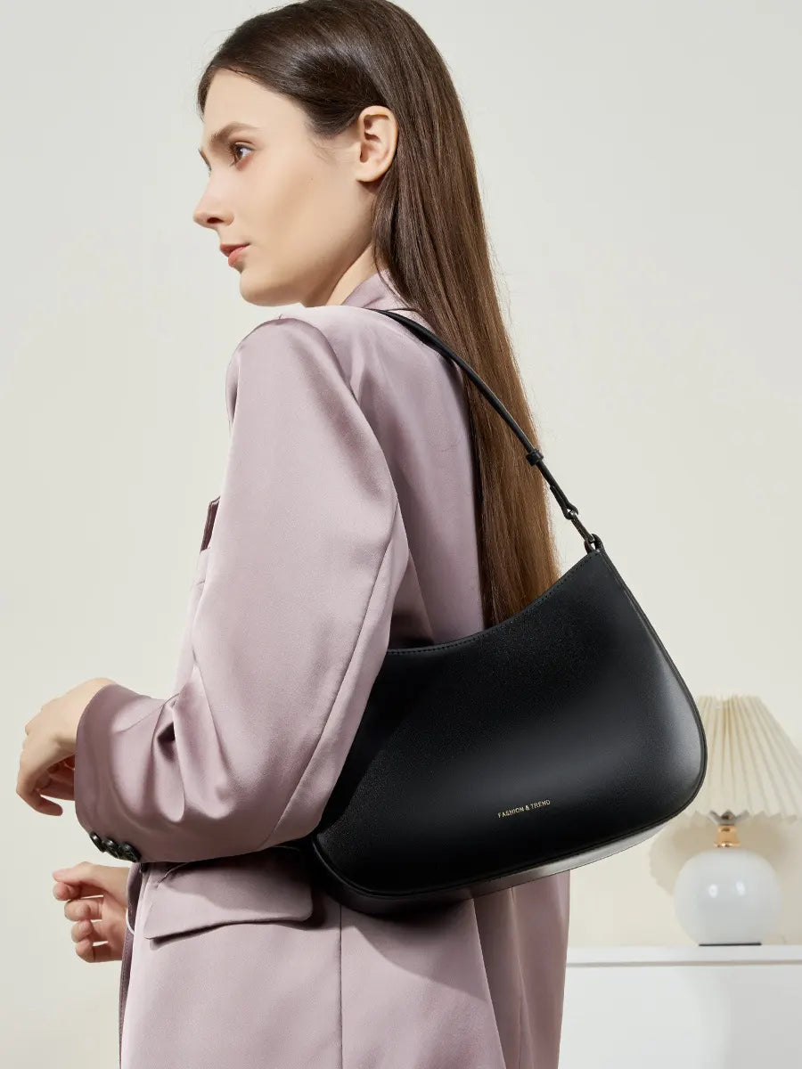 Woman carrying a black handbag against a neutral background