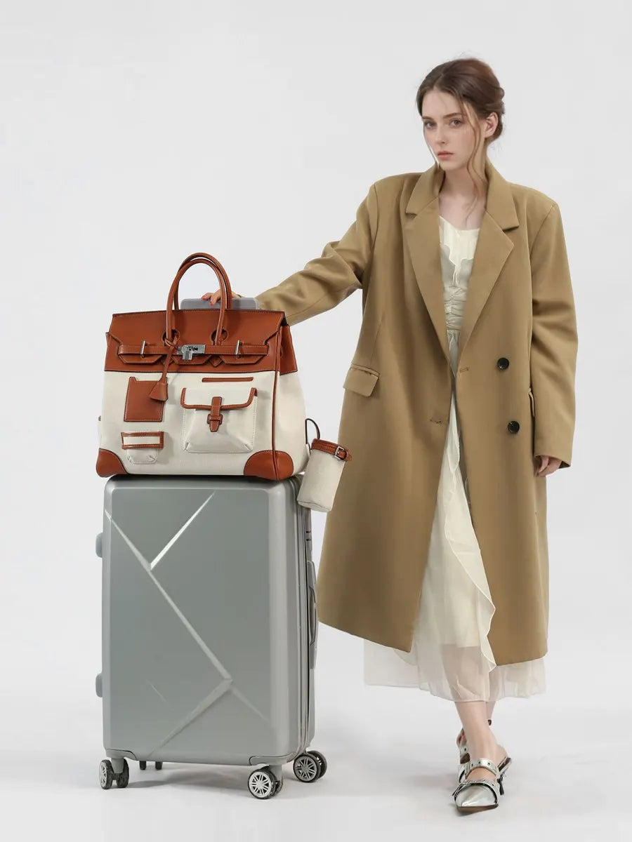 Woman in a beige coat with a brown and white handbag and silver suitcase on a white background