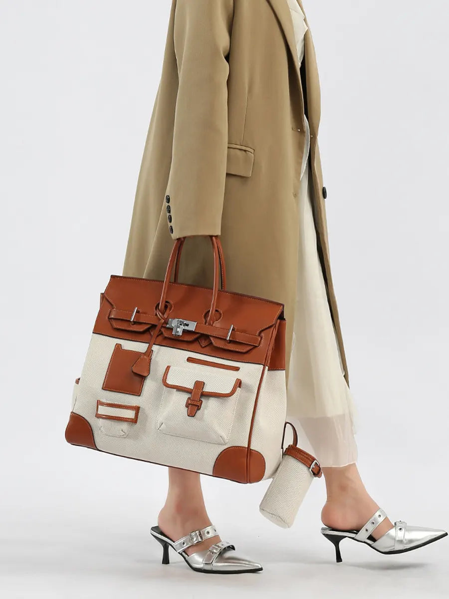 Person wearing a beige coat and holding a brown and white handbag on a light gray background