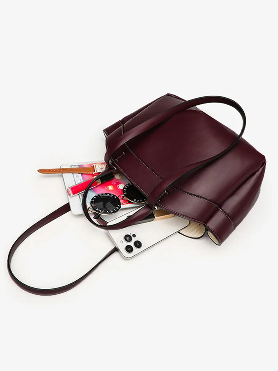 Brown leather handbag with phone, cards, and wallet on a white background