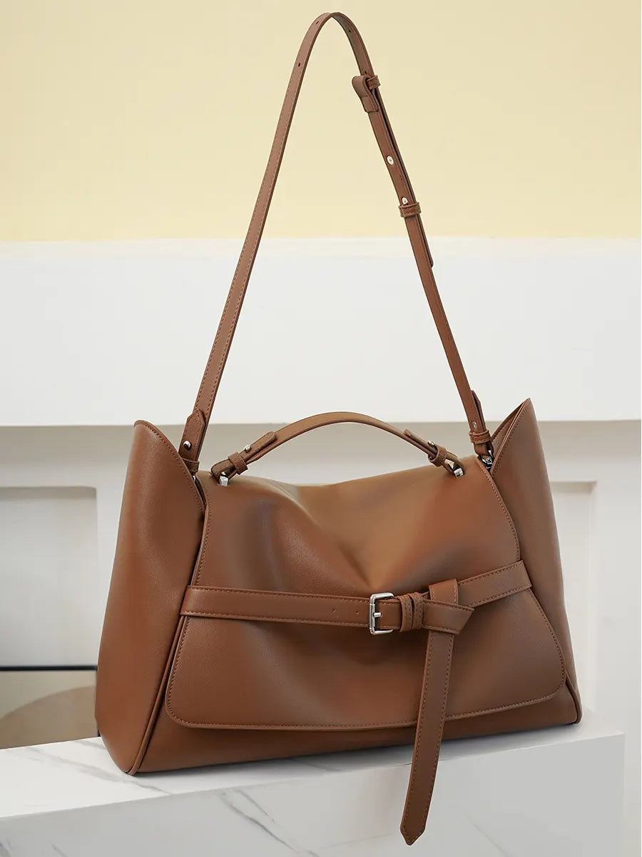 Brown leather handbag with a strap on a light background