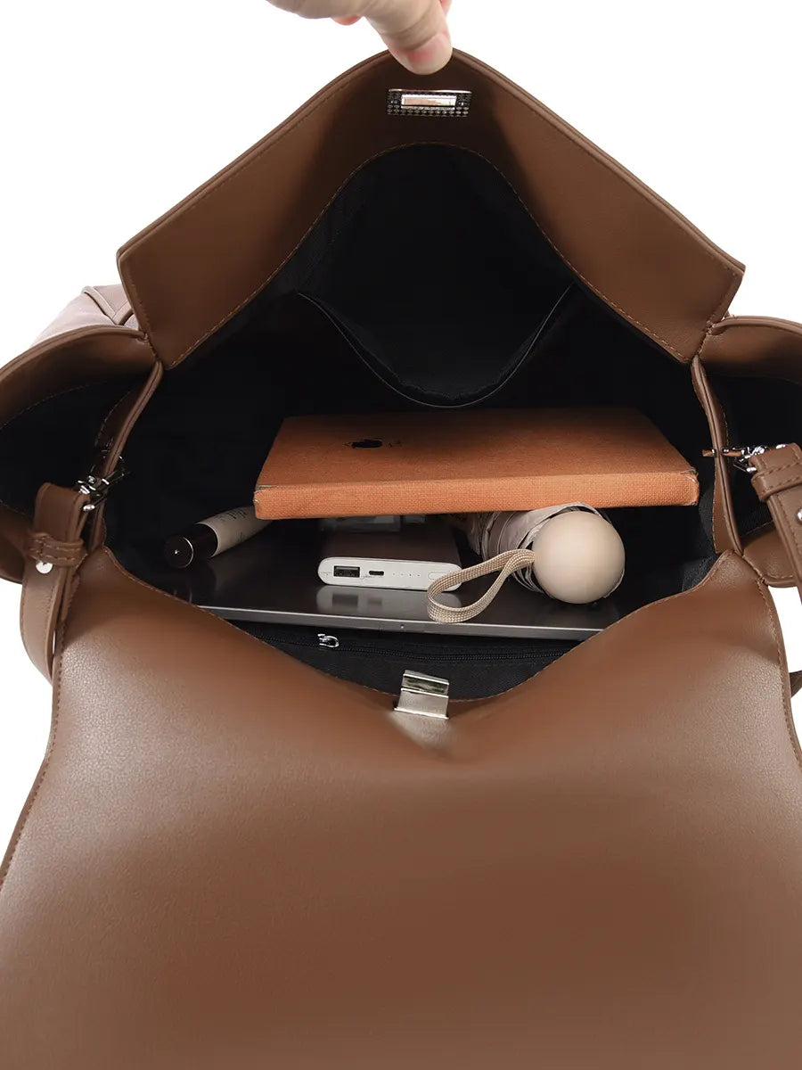 Brown leather bag with a laptop and accessories inside on a white background