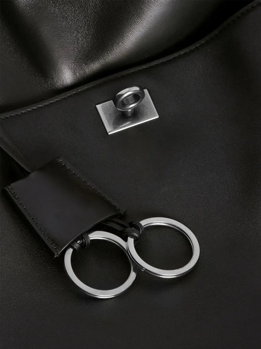 Black leather bag with metal clasp and keychain on a black background