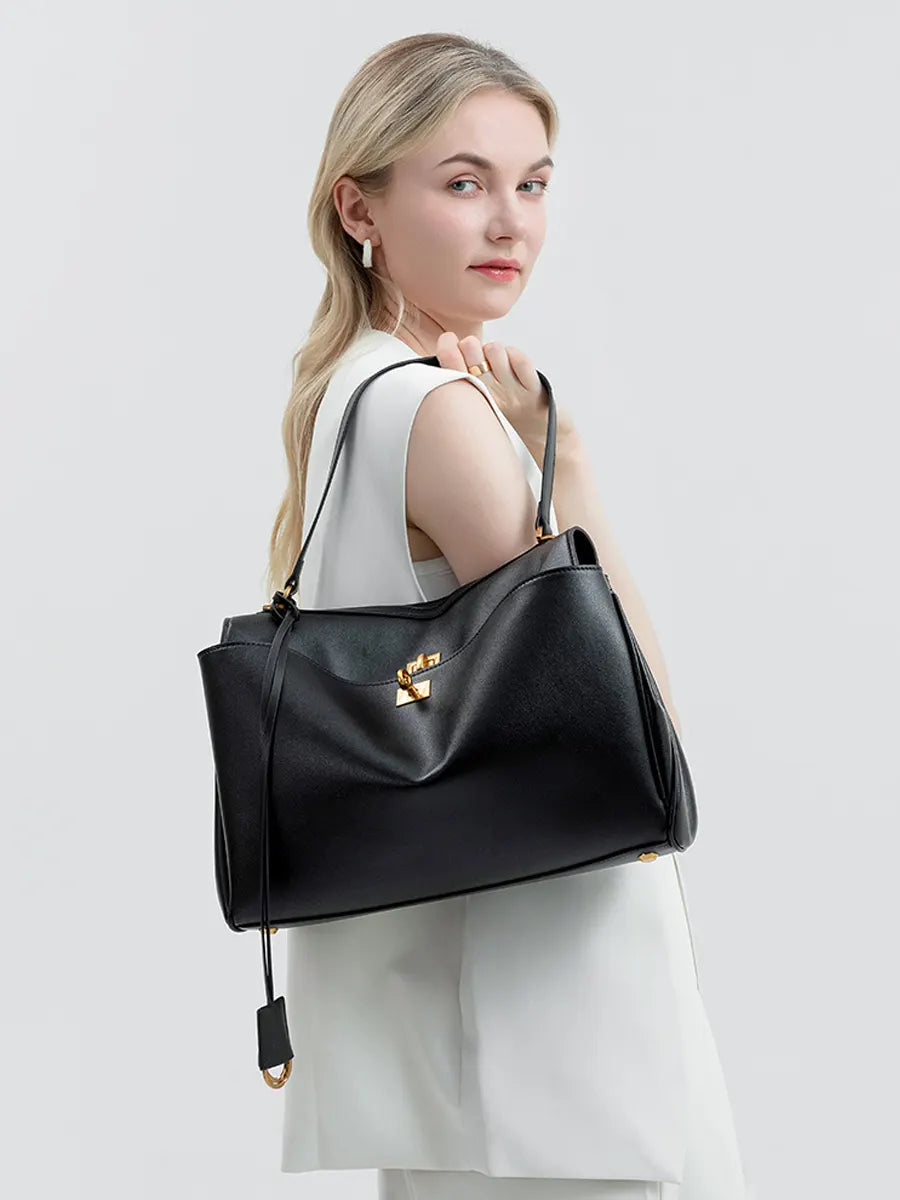Woman holding a black handbag with a gold clasp on a light gray background