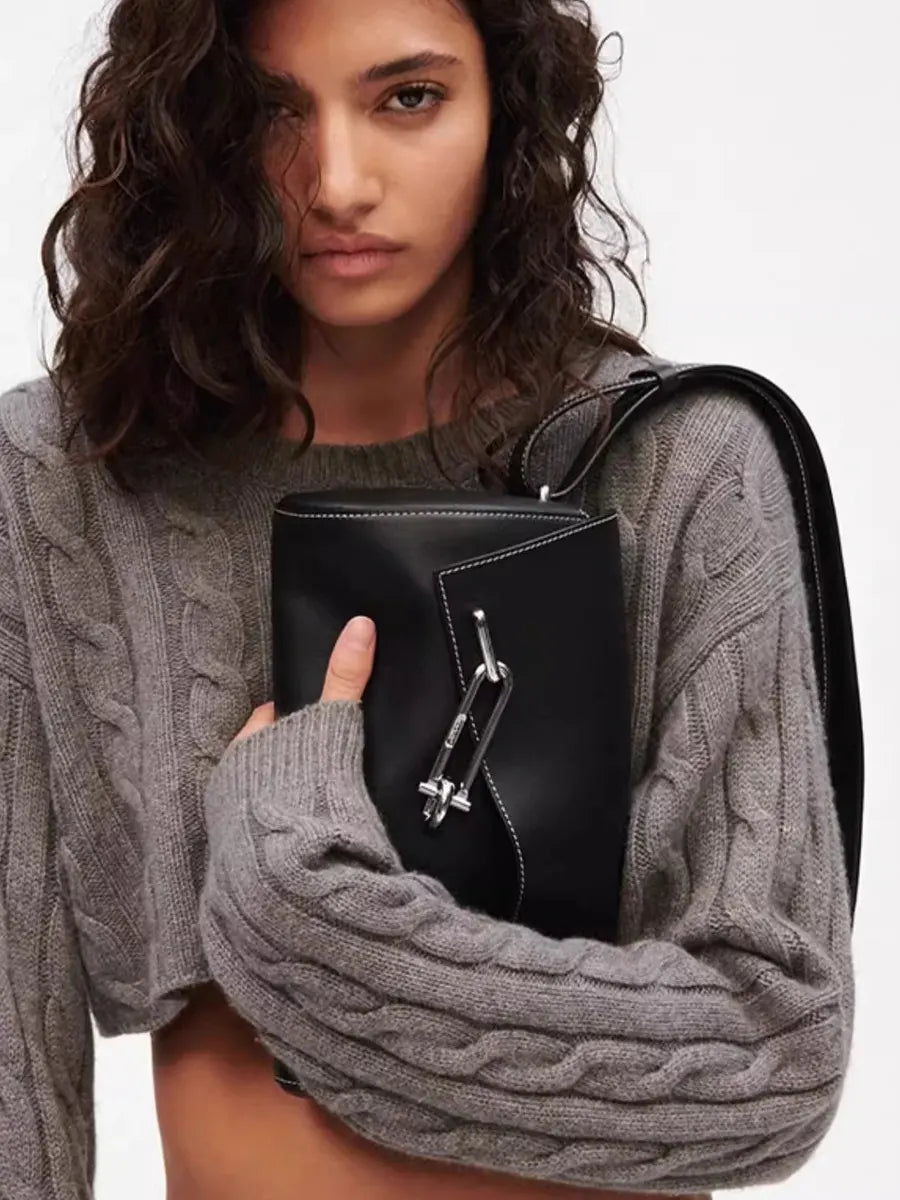 Woman holding a black leather handbag against a neutral background