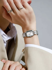 Close-up of a person's wrist wearing a silver watch with a neutral background