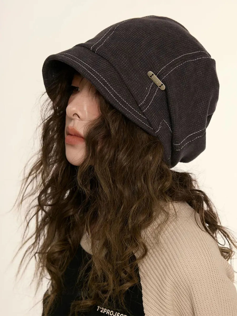 Person wearing a dark denim bucket hat on a plain background