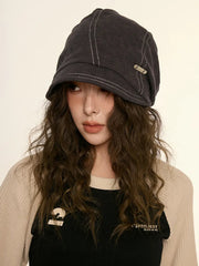 Person wearing a dark gray cap with a beige background