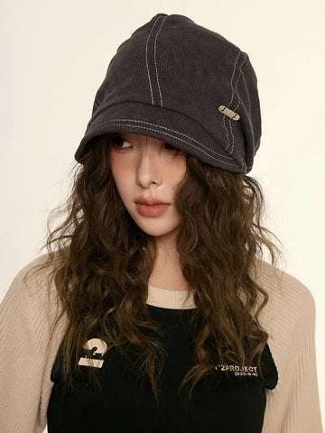 Person wearing a dark gray cap with a beige background