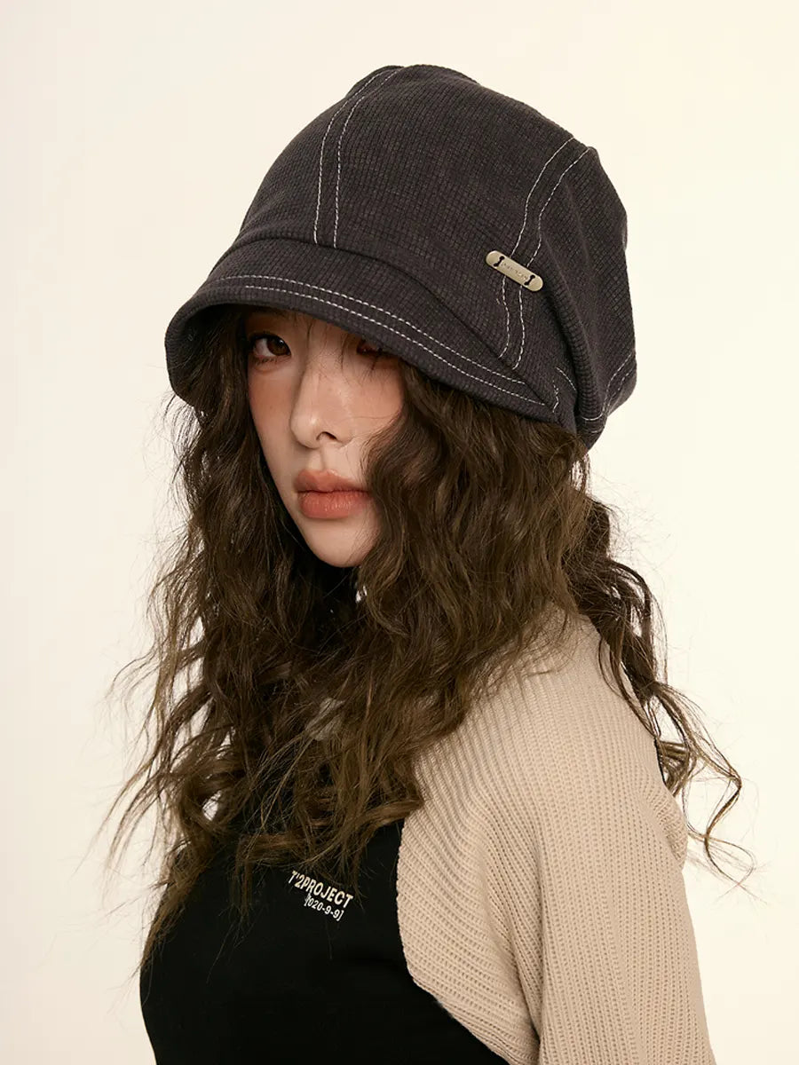 Woman wearing a dark denim cap against a plain background