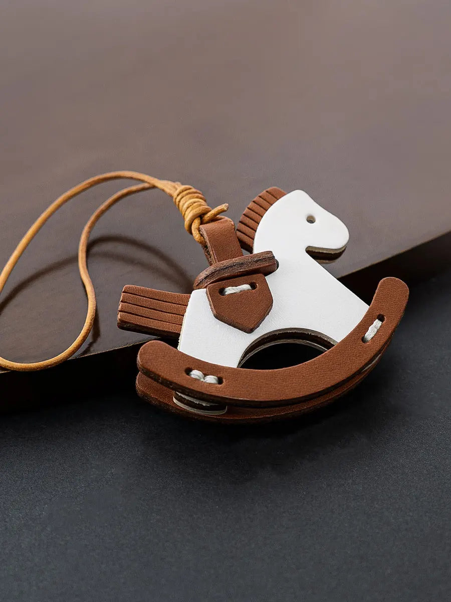 Leather rocking horse keychain on a dark surface