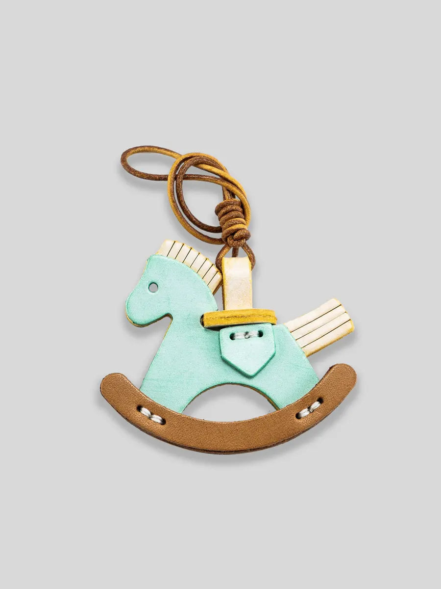 Riding horse keychain with a gold saddle on a light gray background