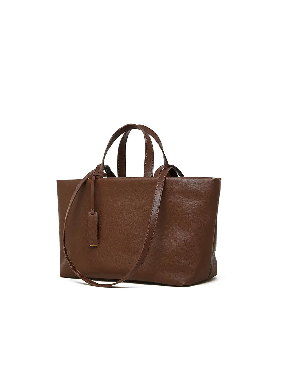 Brown leather tote bag with a shoulder strap on a white background