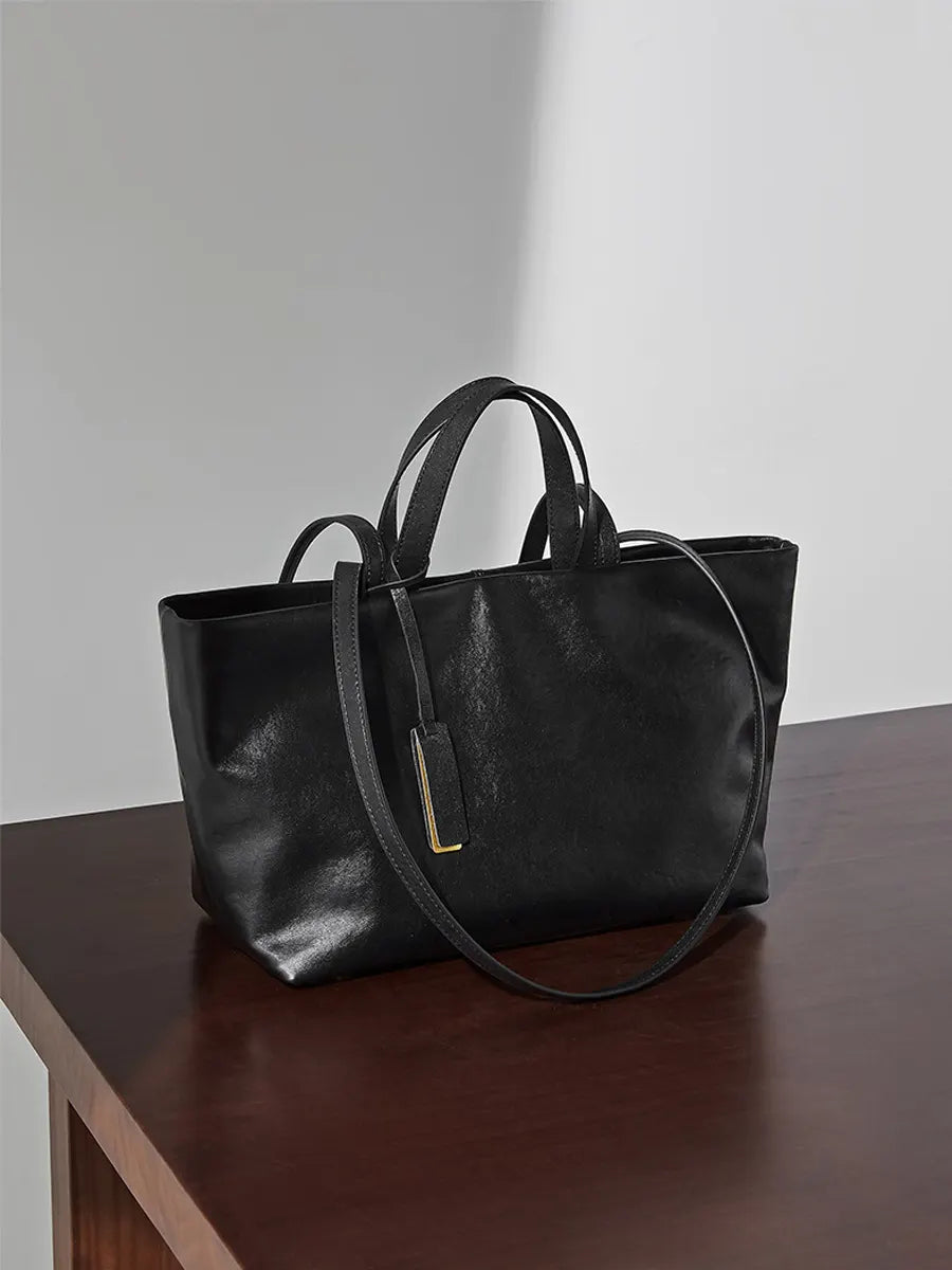 Black leather handbag on a wooden surface with a plain background