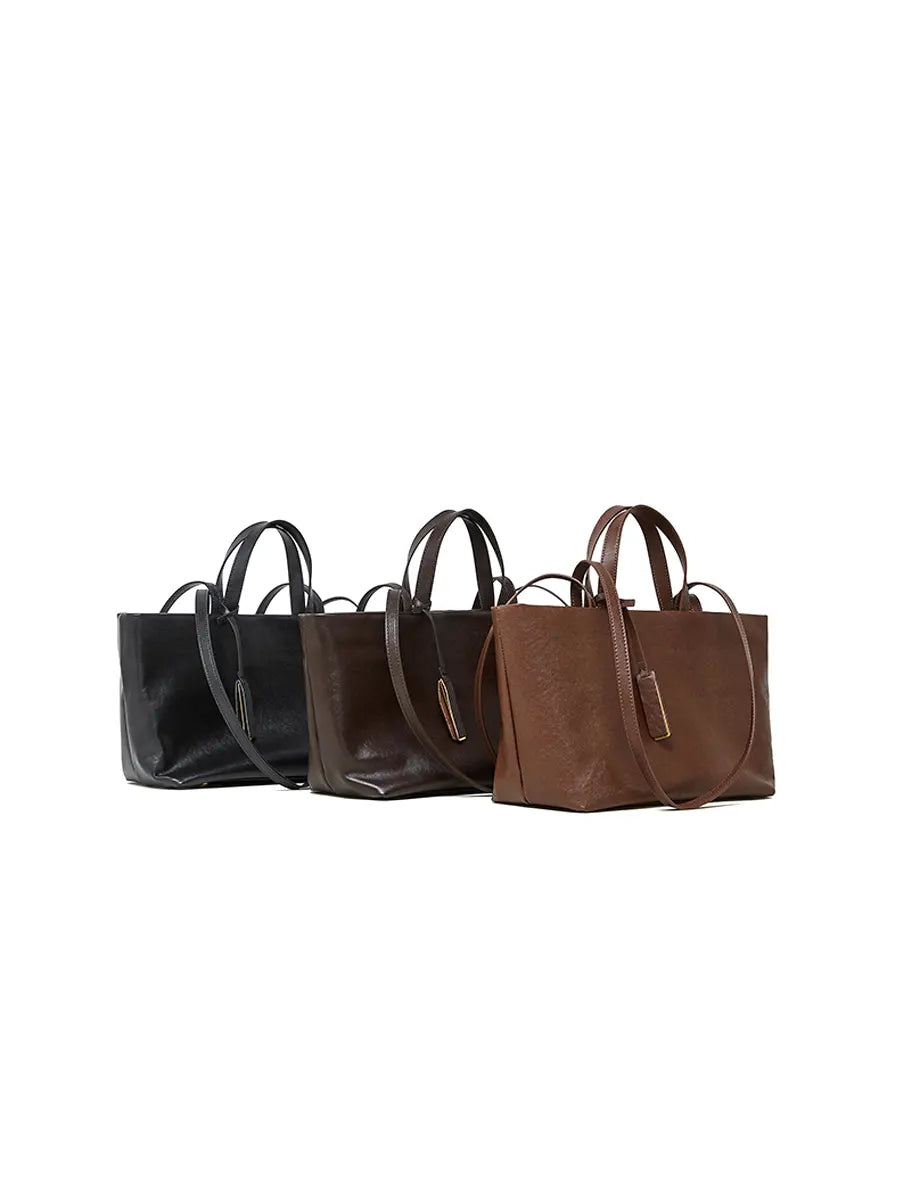 Three leather handbags in black, brown, and another brown shade on a white background