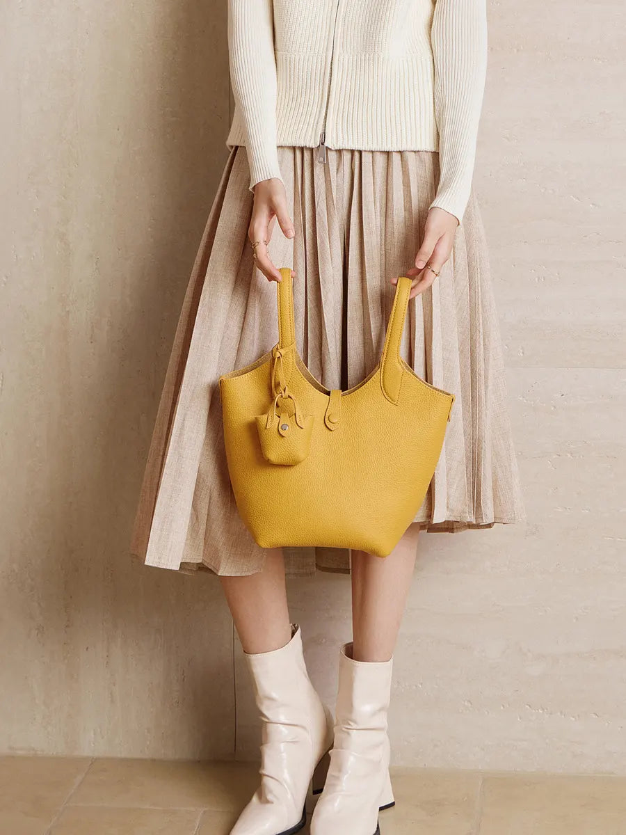 Person holding a yellow handbag against a beige background