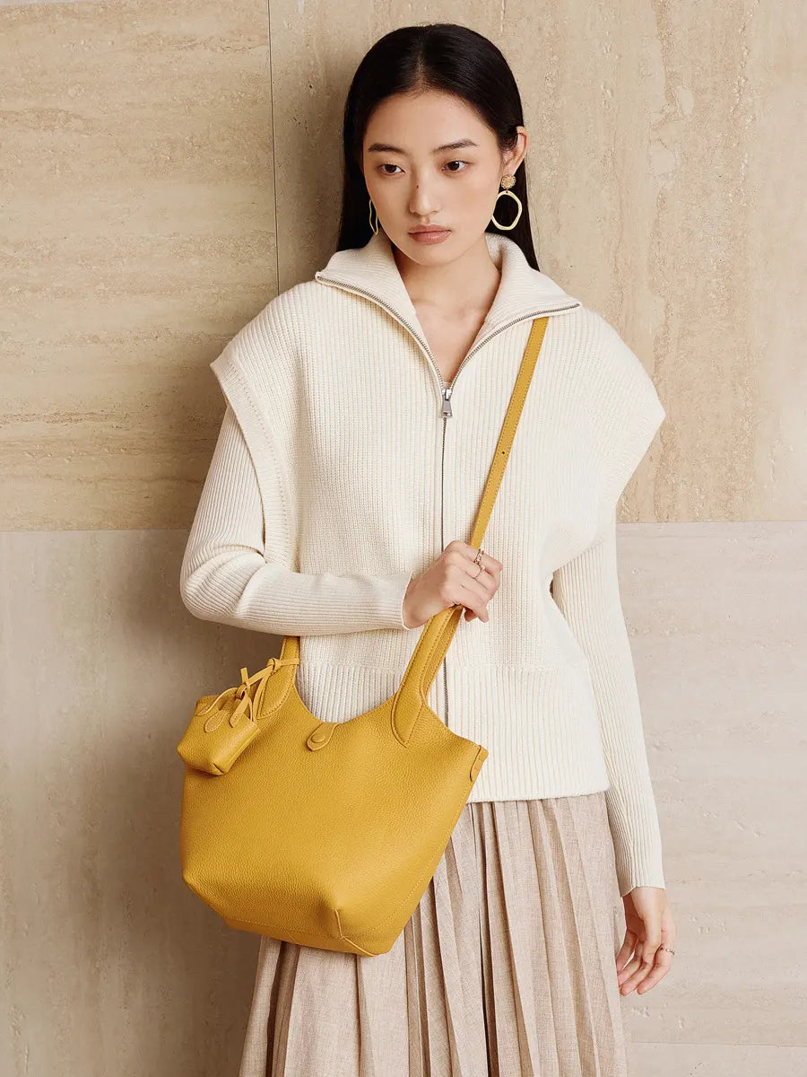 Woman holding a yellow handbag against a beige wall