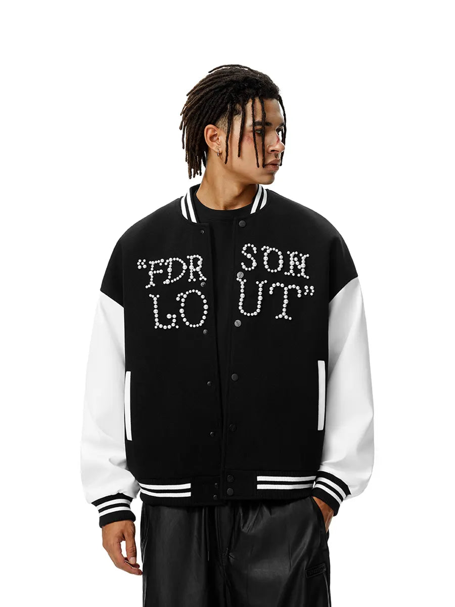 Person wearing a black and white varsity jacket with rhinestone text on a white background