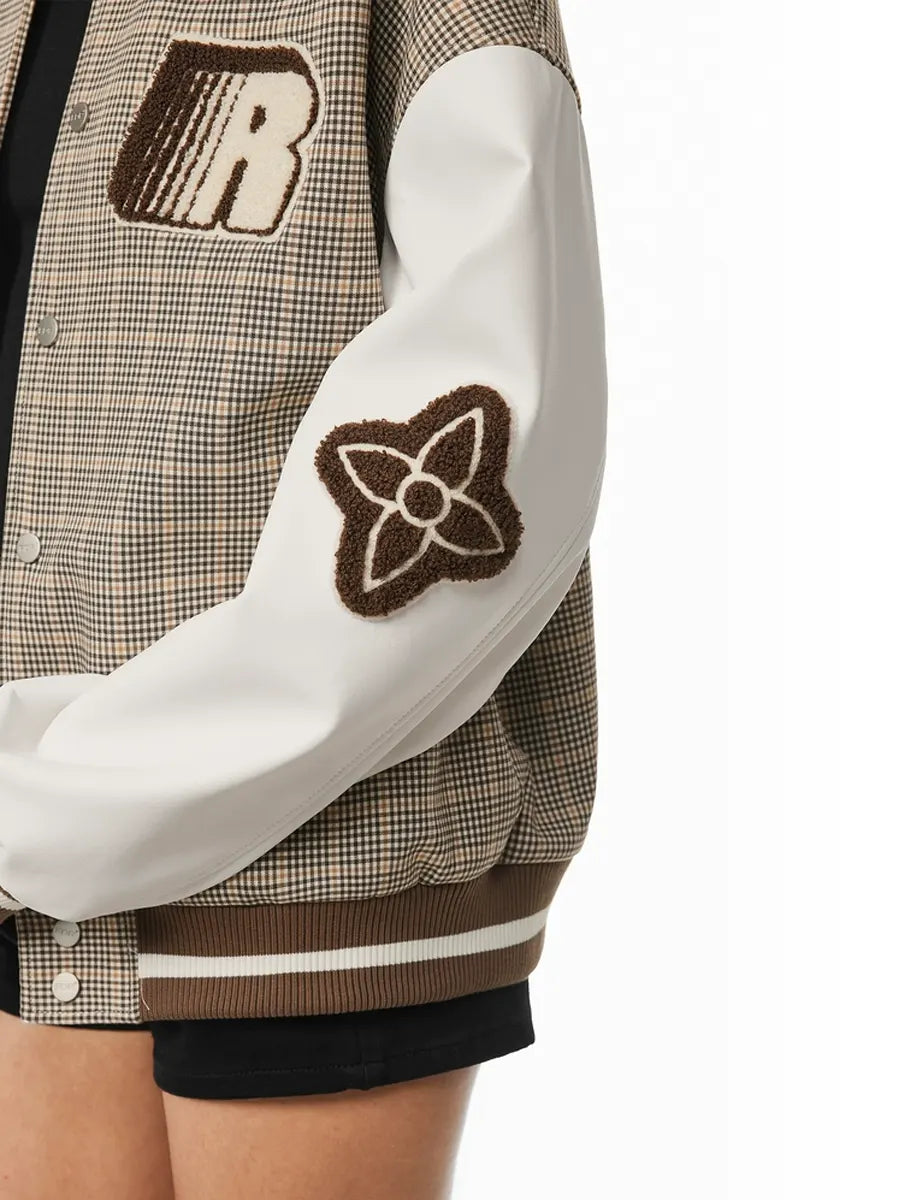 Close-up of a varsity jacket with plaid pattern and embroidered patches on a white background