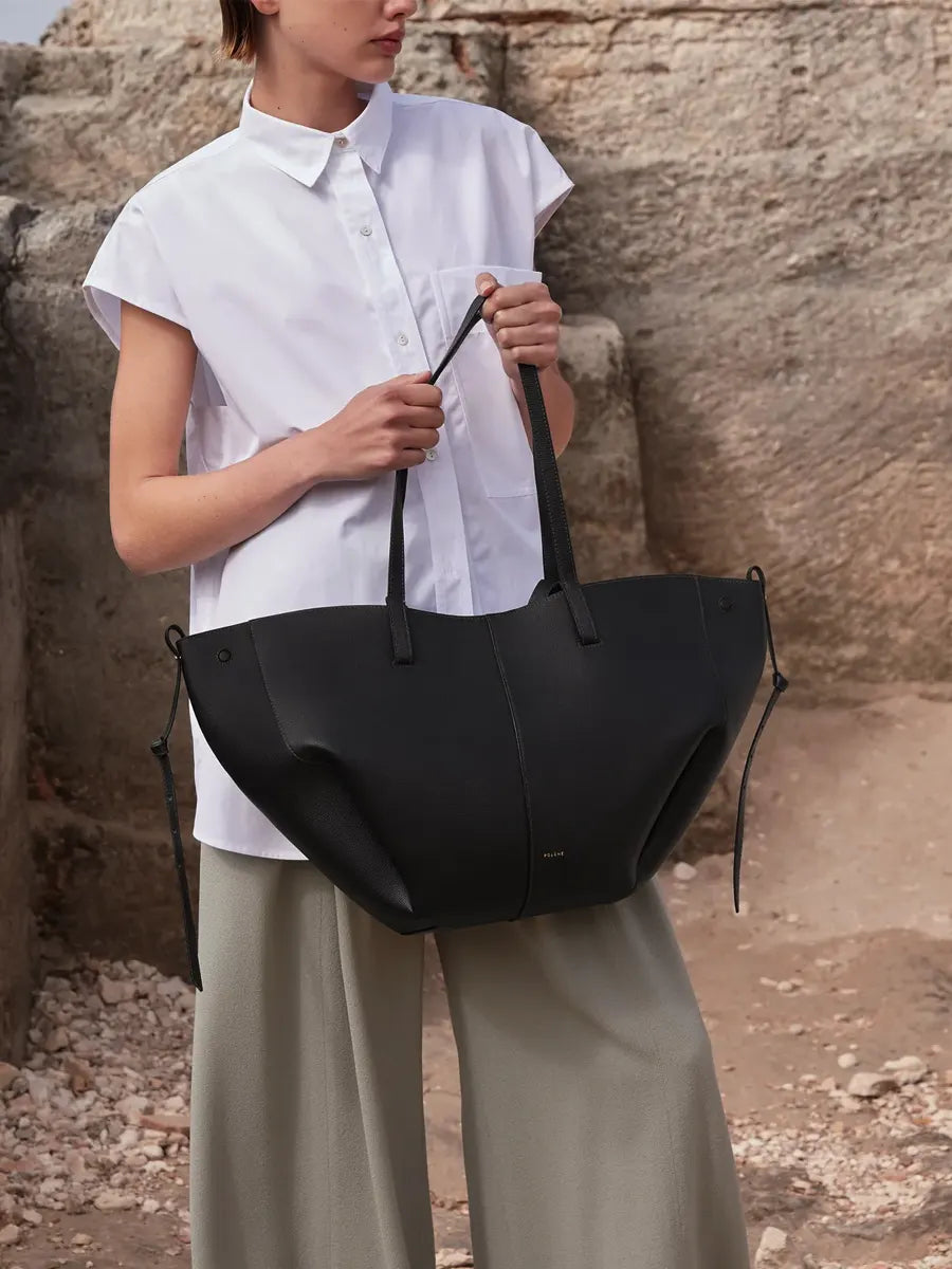 Person holding a black bag against a stone wall background