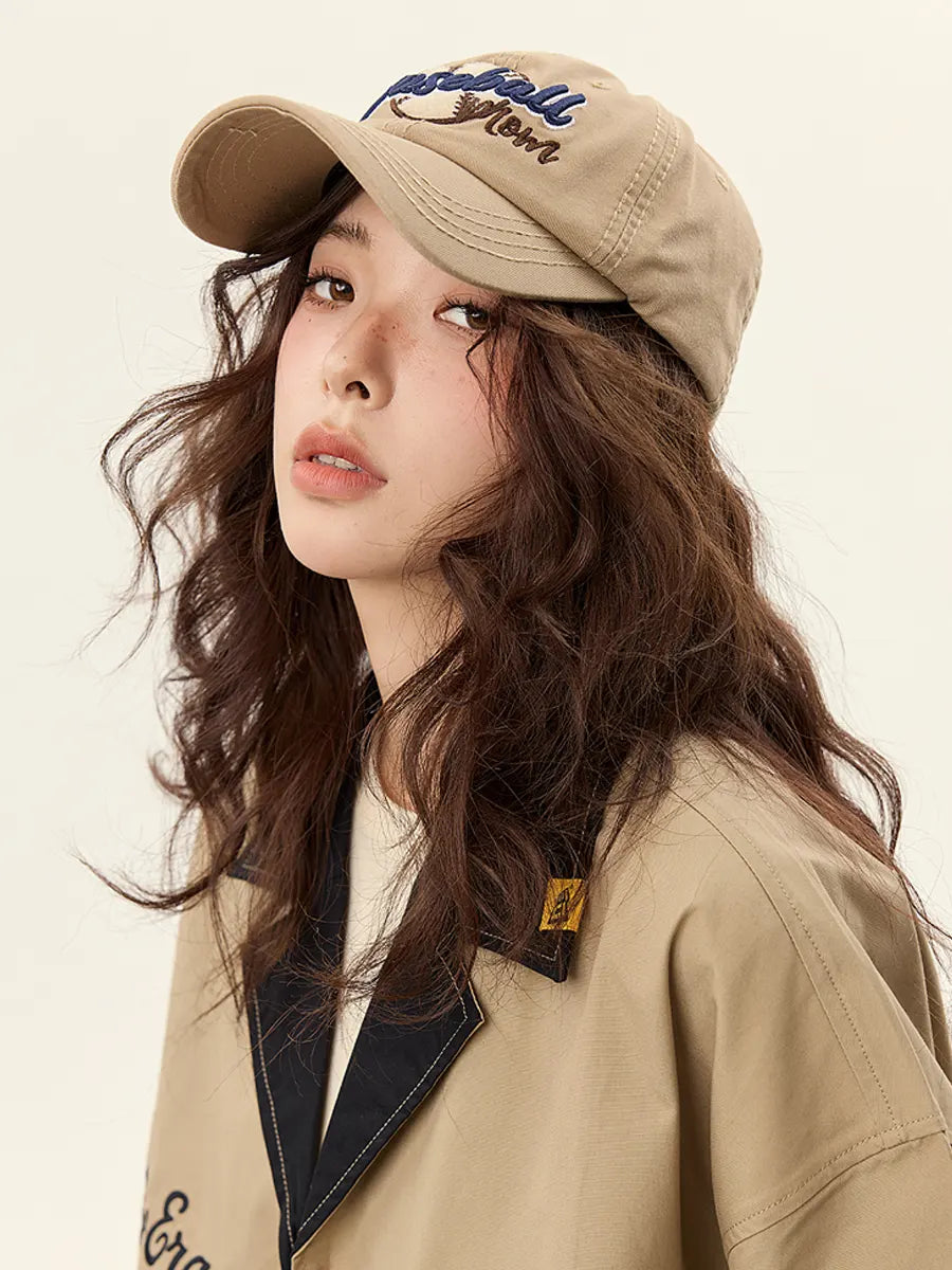Woman wearing a beige cap and jacket with a neutral background