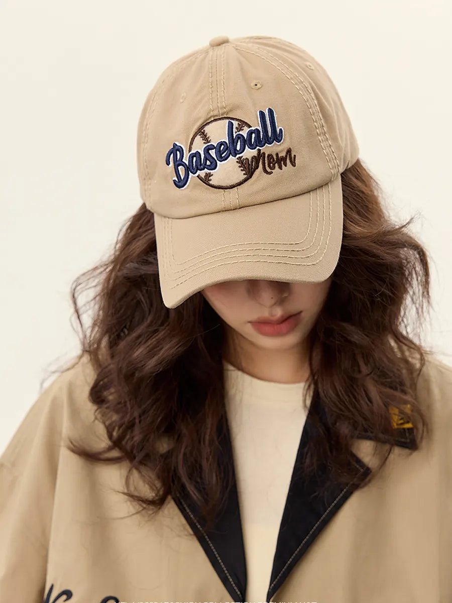 Person wearing a beige cap with 'Baseball Mom' text on a plain background