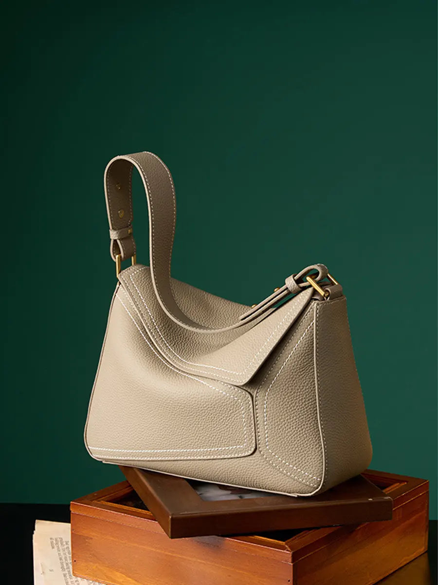 Beige handbag on a wooden stand against a green background