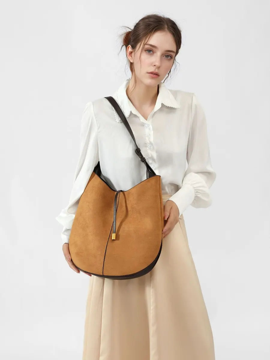 Woman holding a tan leather bag against a white background