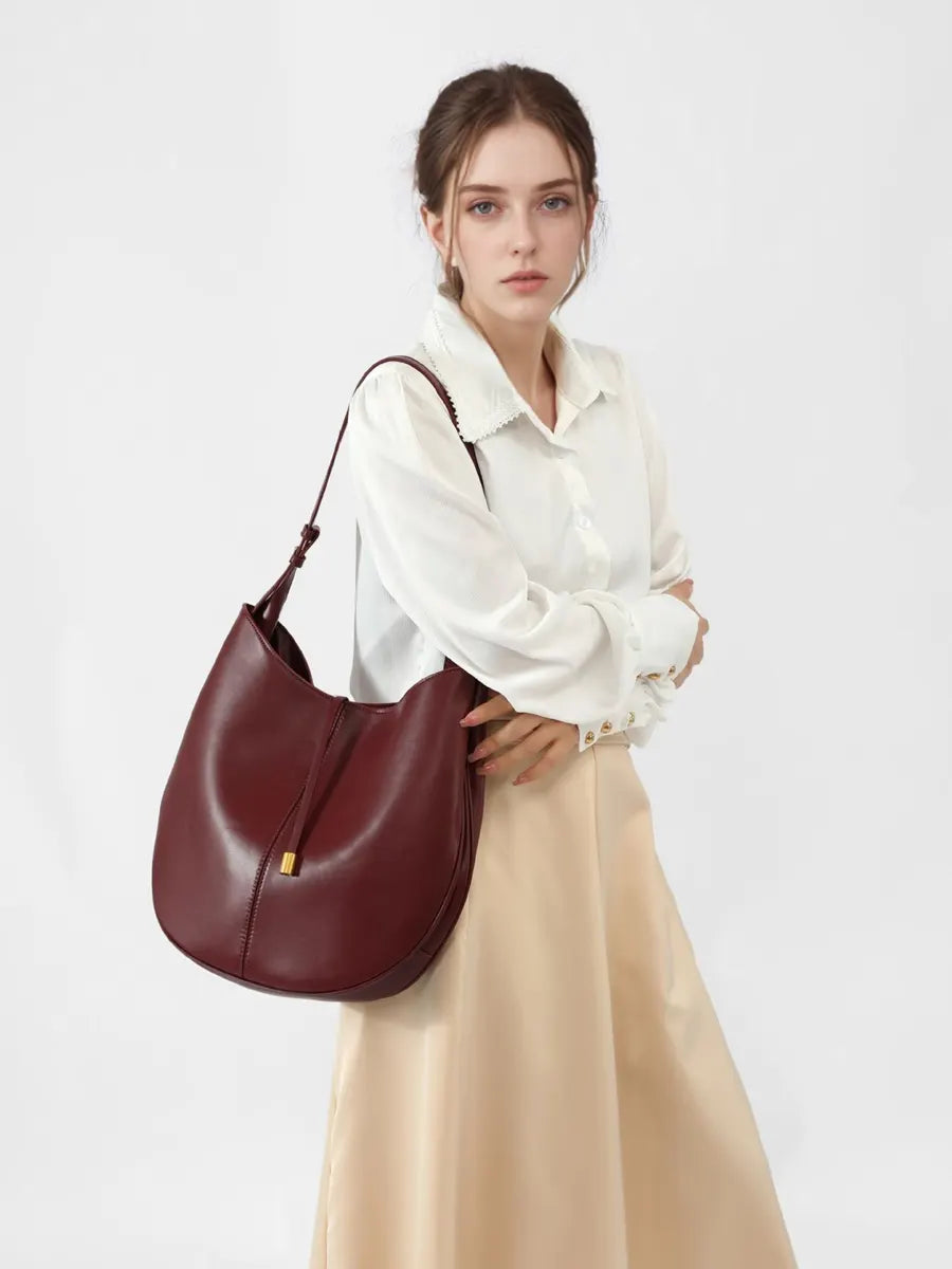 Woman holding a maroon handbag against a white background