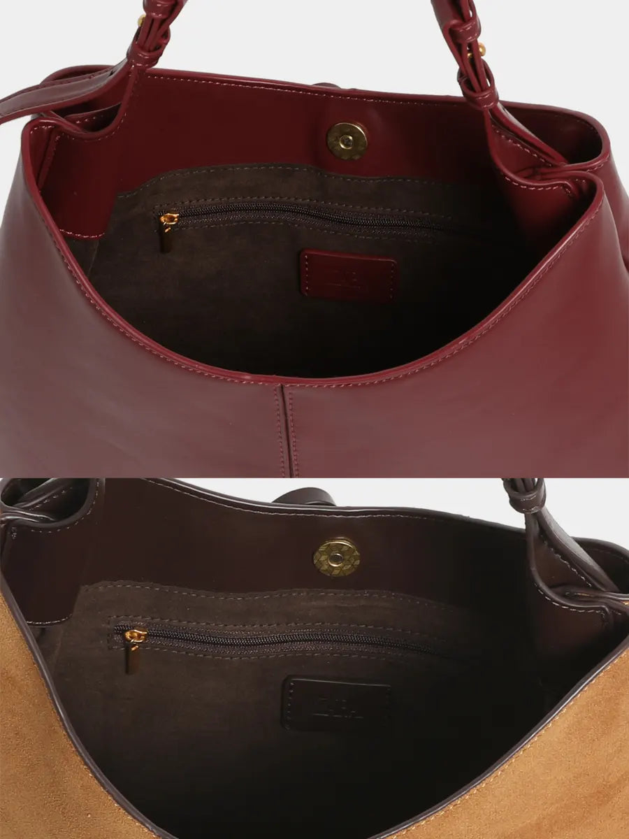 Close-up of a maroon handbag with a gold clasp on a white background.