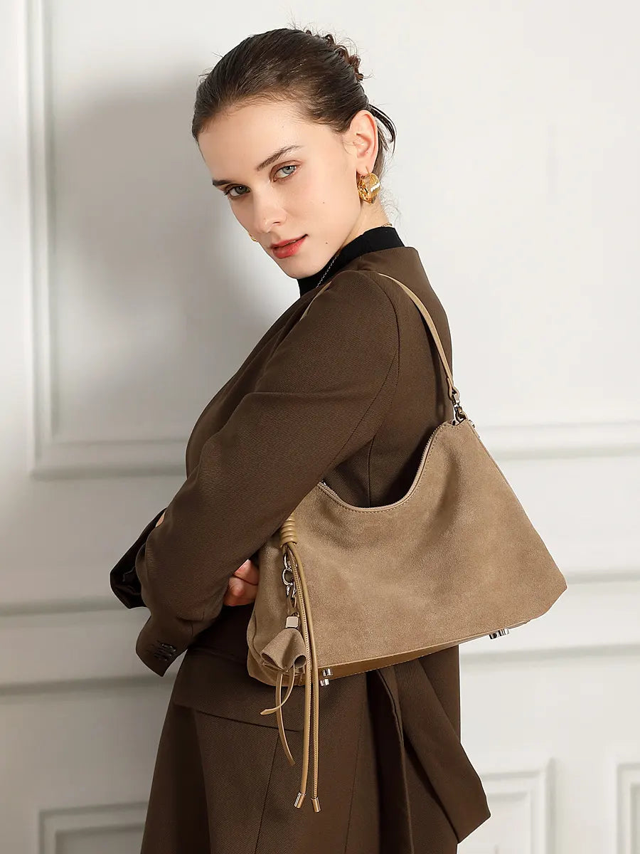 Woman holding a brown handbag against a white wall