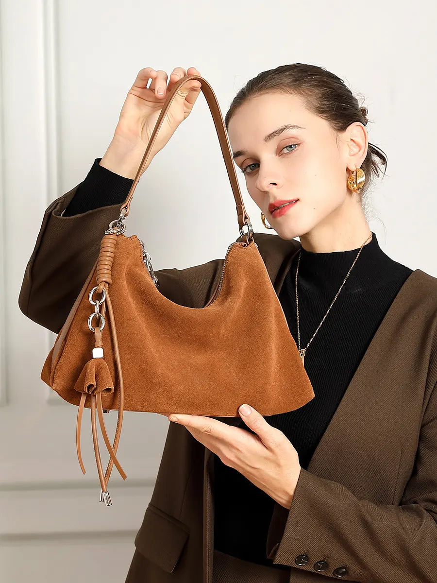 Woman holding a brown leather handbag against a neutral background