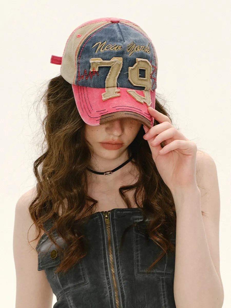 Person wearing a denim and pink cap with 'Neon Miami 79' text, holding it up to their face.