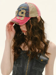 Person wearing a pink and blue baseball cap with '19' on a plain background