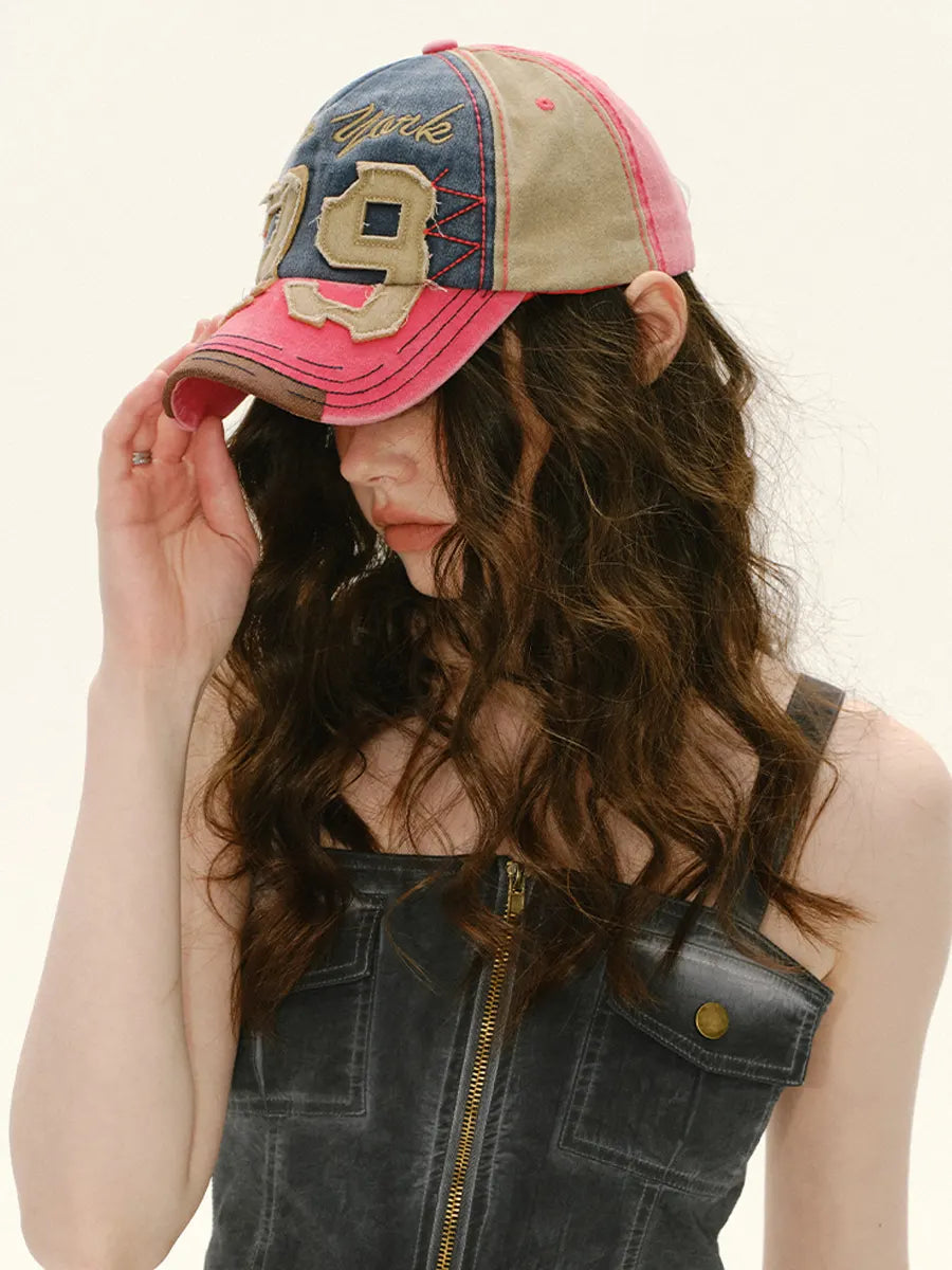 Person wearing a pink and blue baseball cap with '19' on a plain background