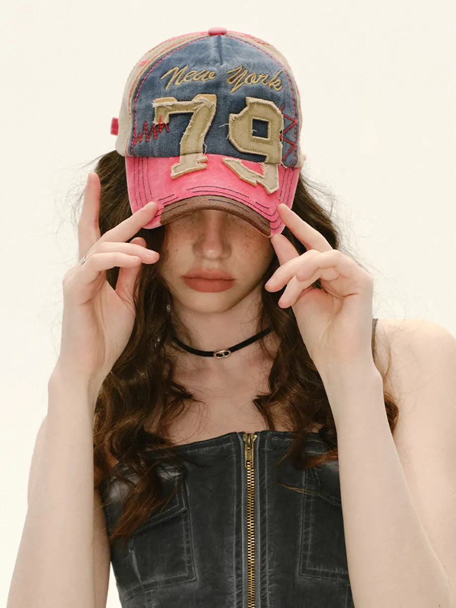 Person wearing a pink and denim cap with 'New York 79' text on a white background